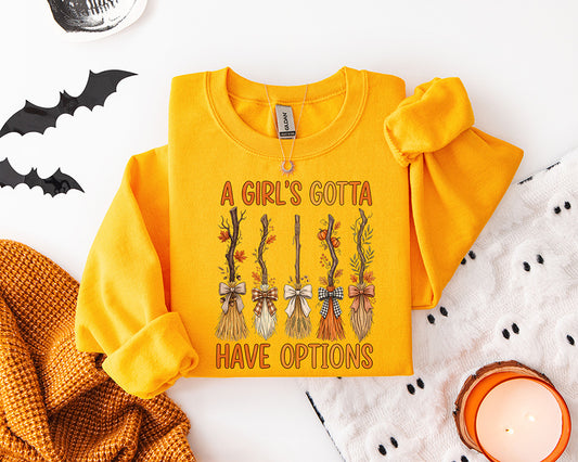 A Girls Gotta Have Options Halloween DTF transfer featuring five whimsical witch brooms decorated with bows fall leaves pumpkins and greenery