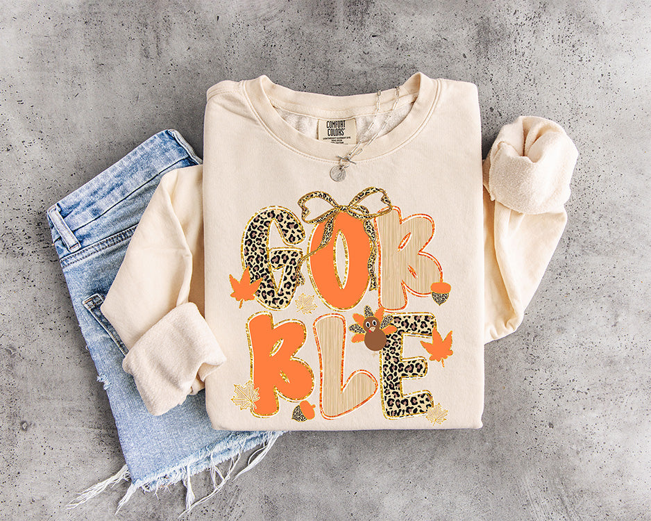 Gobble Thanksgiving DTF transfer featuring orange and leopard print lettering with a leopard bow, turkey, acorns and fall leaves