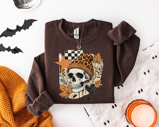 Edgy fall skull DTF transfer featuring a skeleton skull wearing an orange leopard print beanie with autumn leaves, checkerboard accents and black heart details