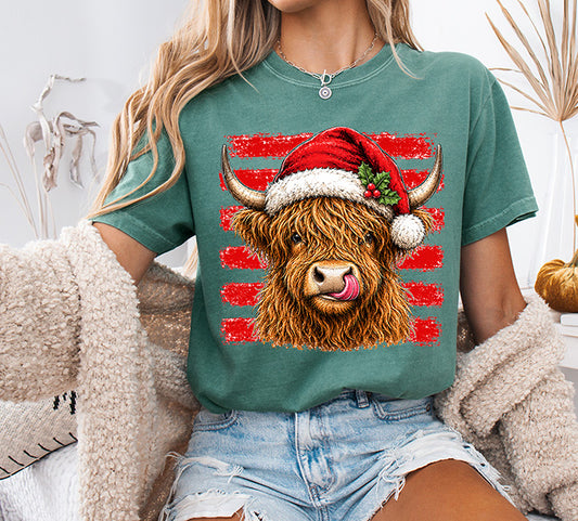 Christmas Highland Cow DTF transfer featuring a shaggy brown Highland cow wearing a red Santa hat with holly and distressed red stripes