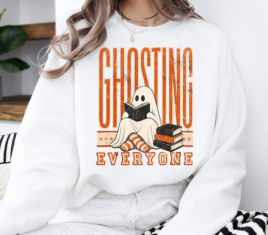 Ghosting Everyone Halloween DTF transfer featuring a cute sheet ghost reading a book with orange striped socks and retro orange lettering