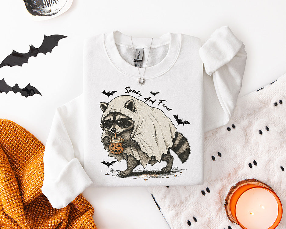 Spooky and Feral Halloween raccoon DTF transfer featuring a raccoon in a ghost costume wearing sunglasses and drinking from a pumpkin coffee cup
