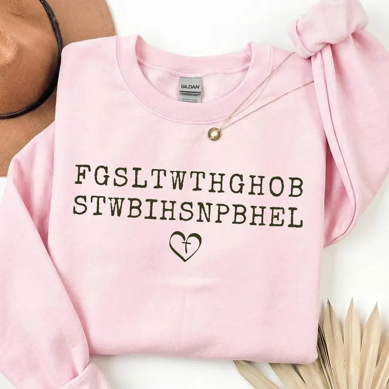 Ready to press white John 3:16 Bible verse acronym DTF transfer featuring the letters FGSLTWTHGHOB STWBIHSNPBHEL with a cross heart graphic, pressed onto a vintage blue mineral wash crewneck sweatshirt.