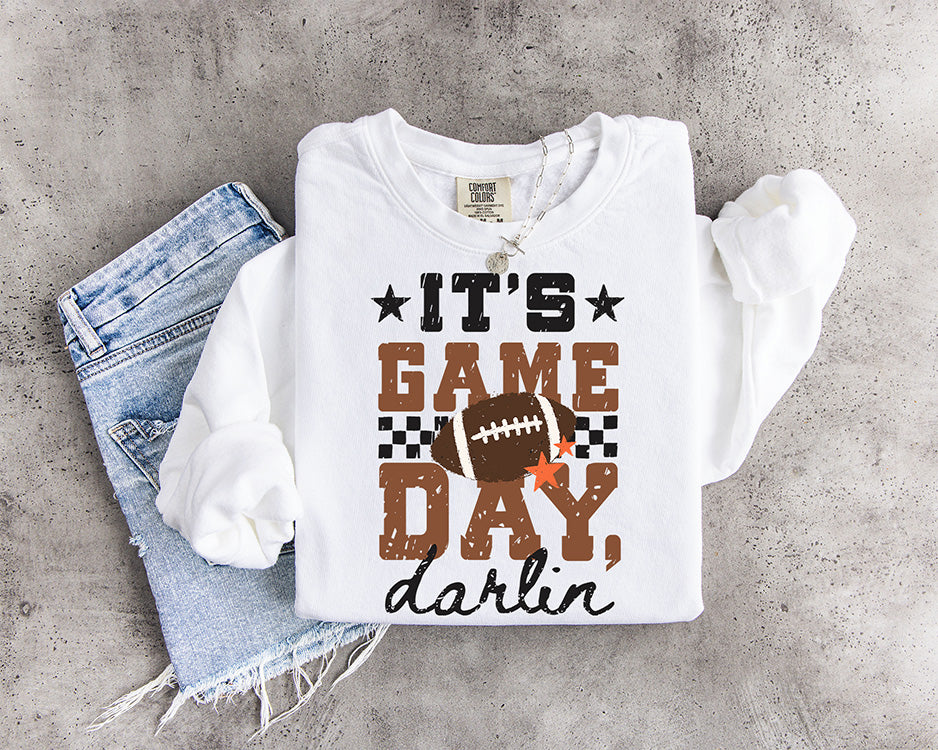 It's Game Day Darlin' DTF transfer with distressed brown and black lettering, football, checkerboard accents and orange stars