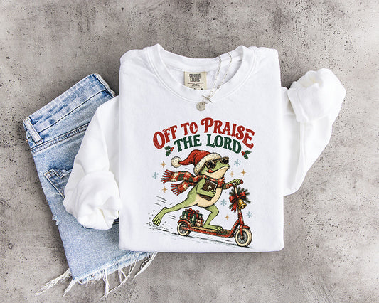 Off to Praise the Lord Christian Christmas DTF transfer featuring a frog in Santa hat carrying a Bible while riding a festive scooter