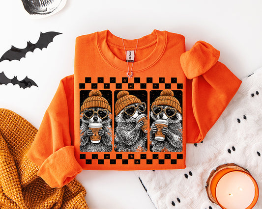 Pumpkin Spice Raccoon fall DTF transfer featuring three raccoons wearing orange beanies and heart sunglasses while drinking pumpkin spice coffee in a black checkerboard frame