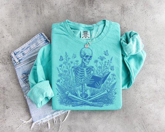 Blue reading skeleton DTF transfer surrounded by wildflowers and butterflies for book lovers