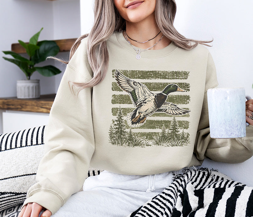 Vintage mallard duck hunting DTF transfer featuring a flying mallard over pine trees with distressed olive green stripes.
