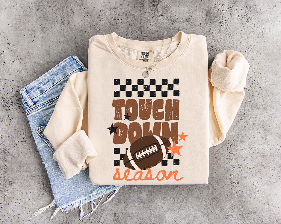 Touchdown Season football DTF transfer with distressed brown lettering, football, black checkerboard pattern and orange stars